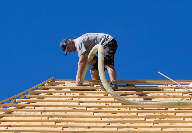 Mann dämmt Dach mit Einblasdämmung | Holz-Hauff in Leingarten