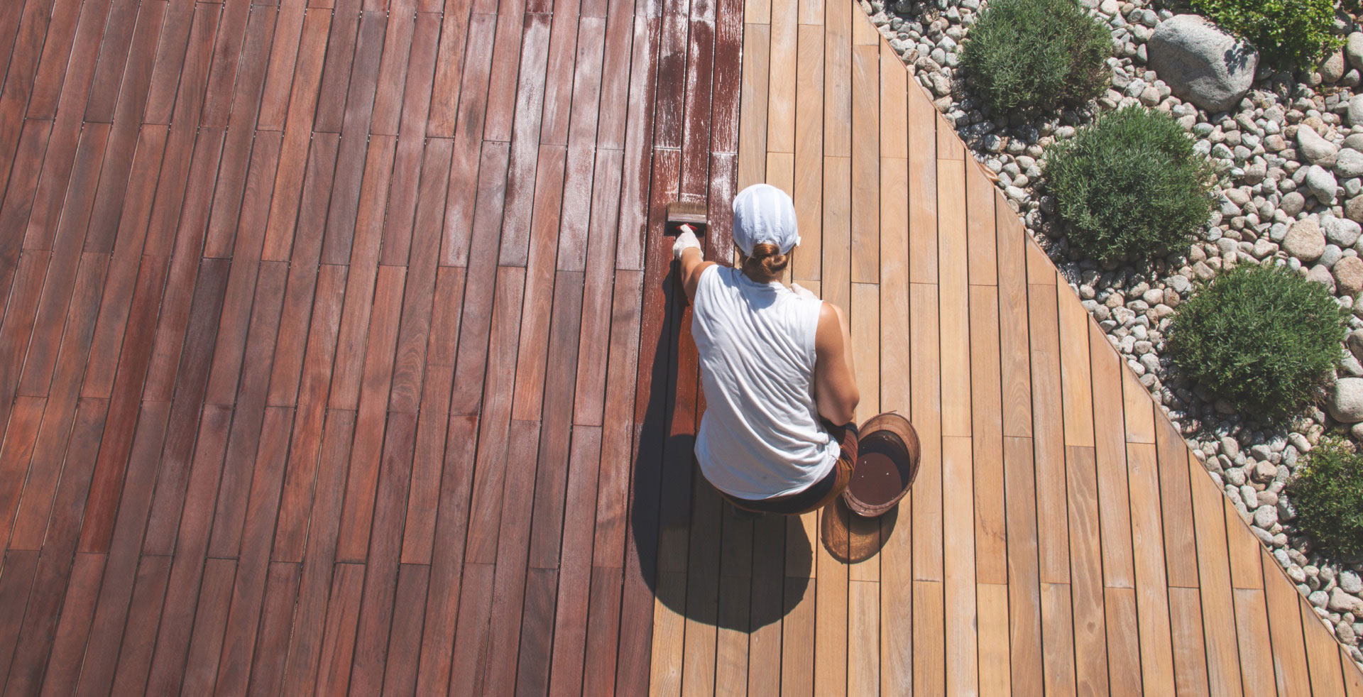 Frau trägt Holzschutz auf Terrassendielen aus Holz auf | Holz-Hauff in Leingarten