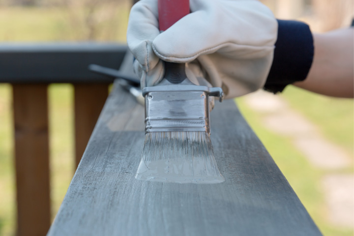 Person trägt pigmentiertes Terrassenöl in Grau auf Holzgeländer auf | Holzschutz | Holz-Hauff in Leingarten