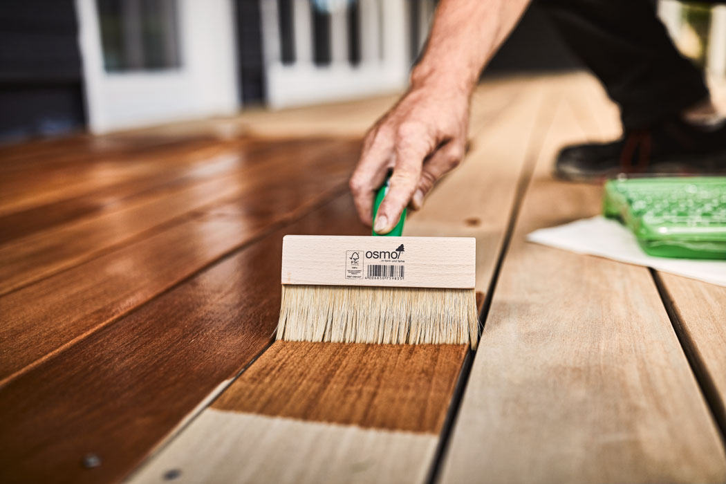 Mann behandelt Holz-Terrassendielen mit pigmentierten Terrassenöl in Braun | Holzschutz | Holz-Hauff in Leingarten